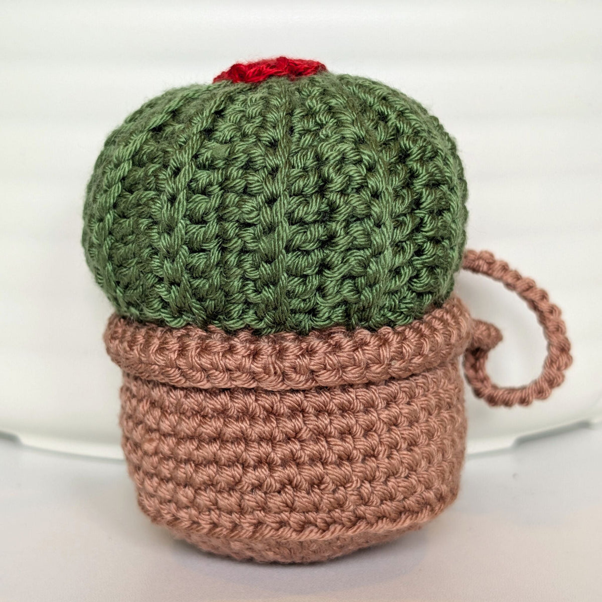 Crocheted moon cactus in a blush brown pot and with a red flower and a string