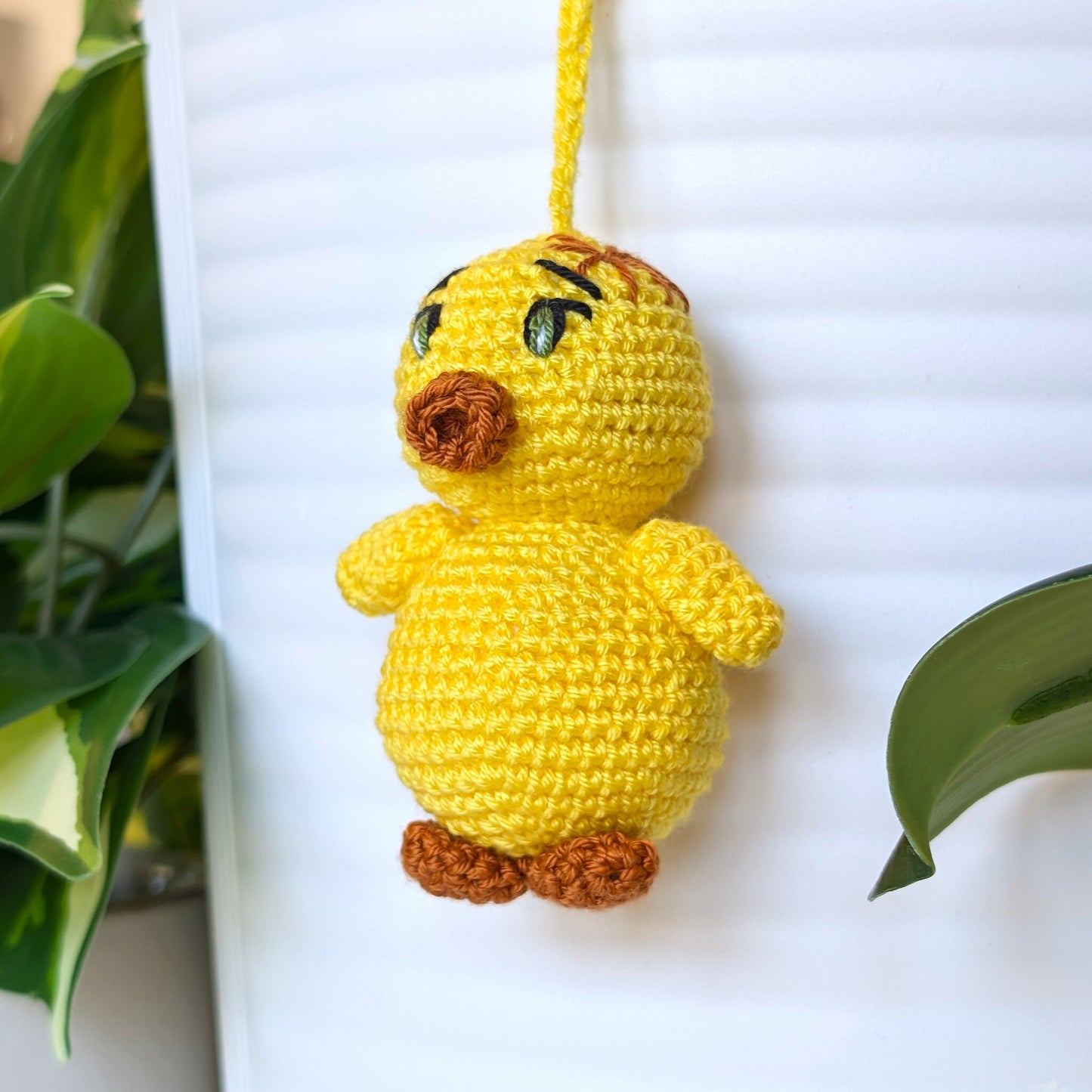 Crocheted yellow chick charm with green eyes and string wearing a star