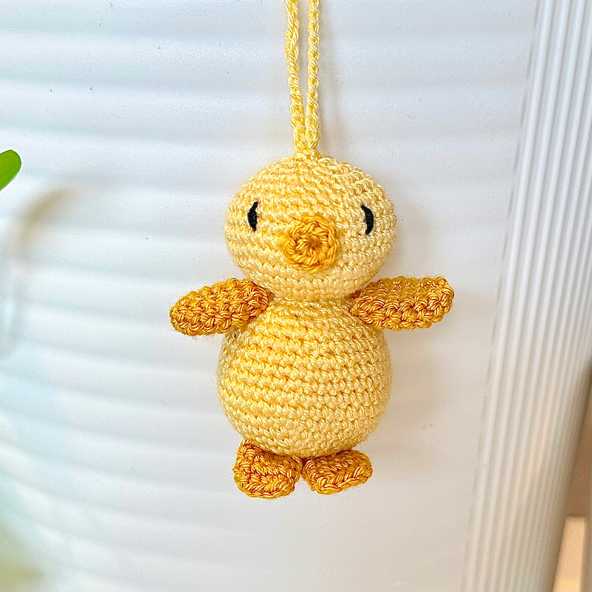 Crocheted light yellow chick with a string