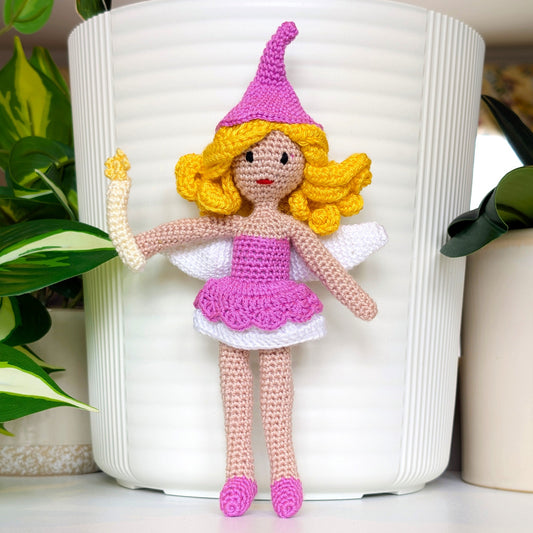 Crocheted fairy doll with pink outfit and yellow hair holding a wand