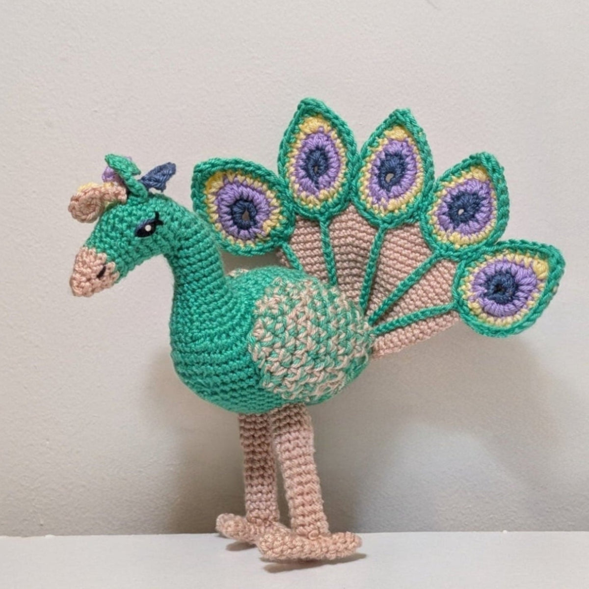 Crocheted peacock toy on a white background