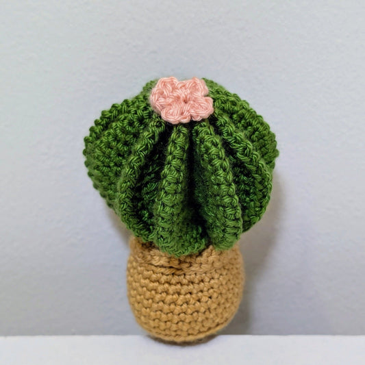 Crocheted cactus with a pink flower on a gray background