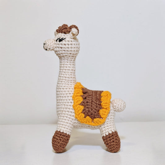 Crocheted alpca toy with brown and yellow details on a white background