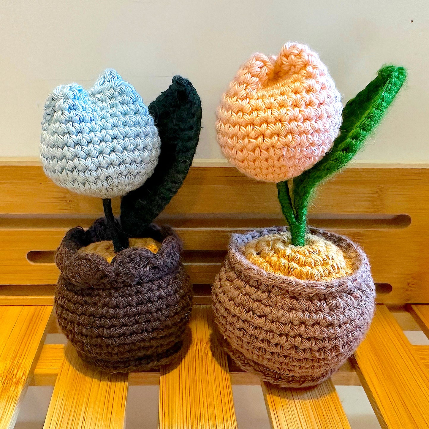 Crocheted plush potted tulip in pastel colors on a wooden surface