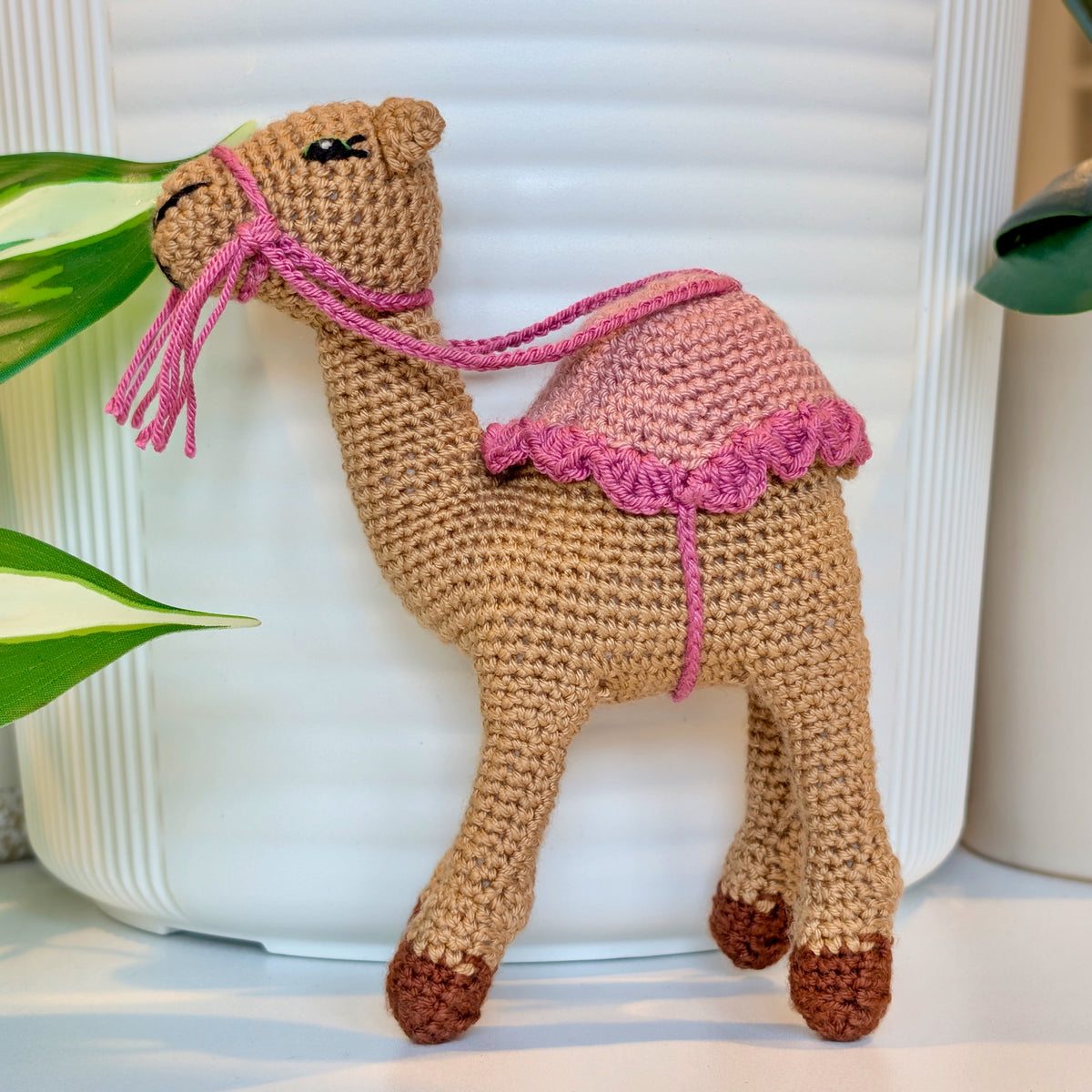 Crocheted sand brown camel wearing a dusty pink Saddle with orchid fringe and bridle