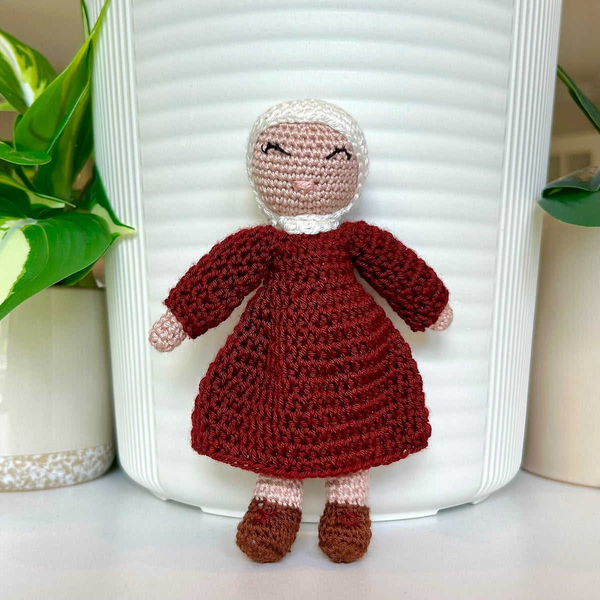 Crocheted doll wearing a white hijab and burgundy dress
