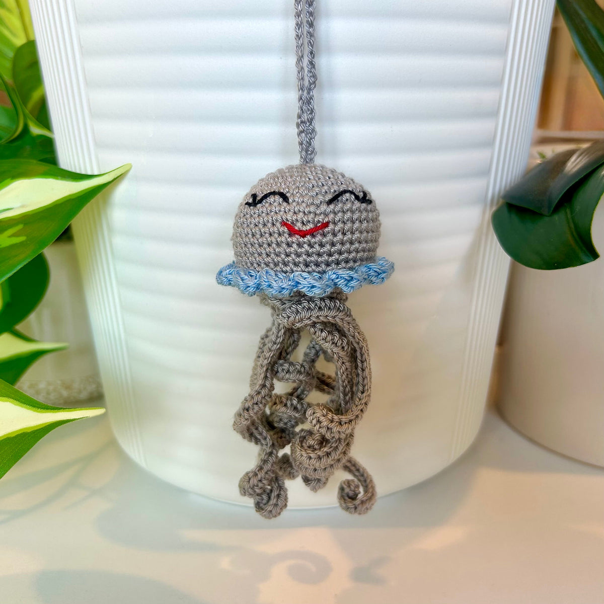 Crocheted gray jellyfish bag charm with light blue trim
