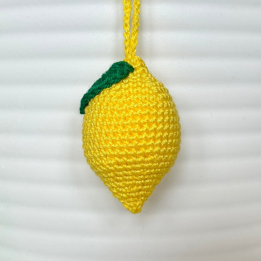 crocheted yellow lemon keychain with a green leaf