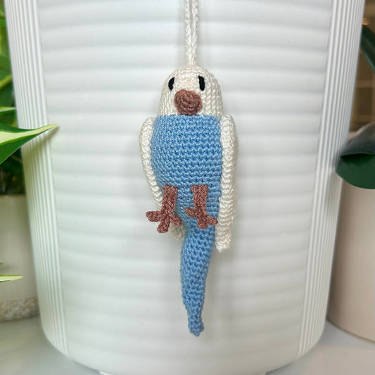 Crocheted parakeet charm with white wings and body and light blue body
