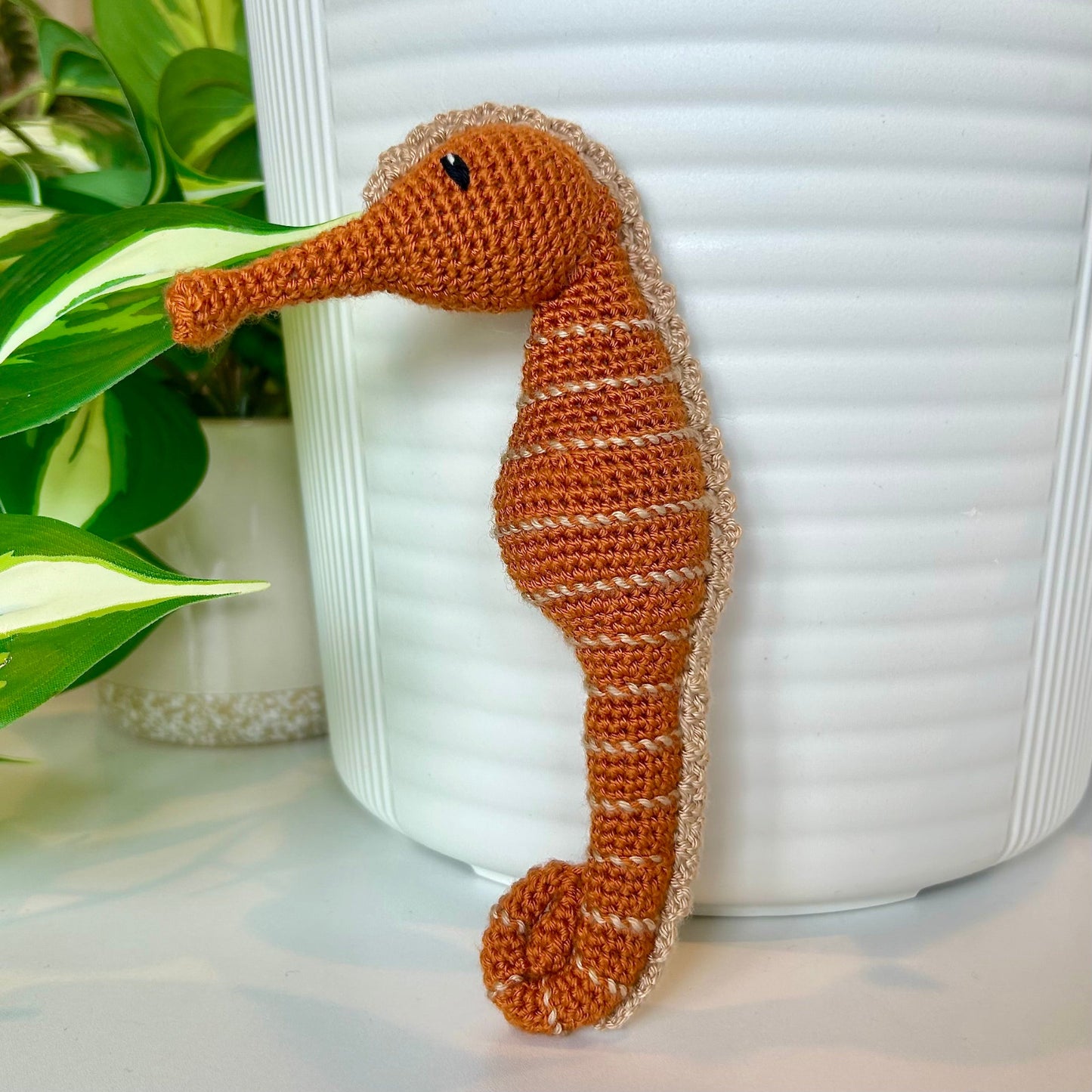 Ginger-colored crocheted seahorse figurine with tan stripes