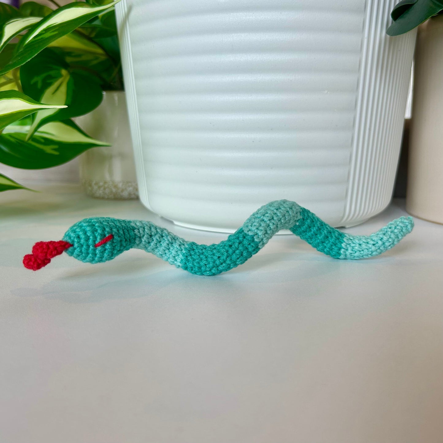Crocheted snake figurine with aqua stripes and a red tongue