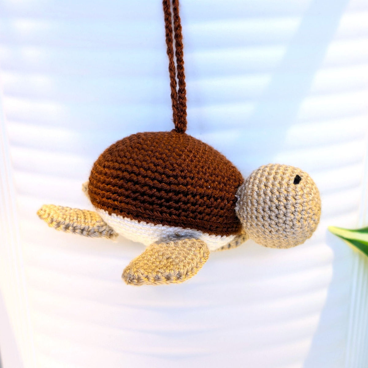 Front view of a crocheted Sea turtle with brown shell with beige body and a string