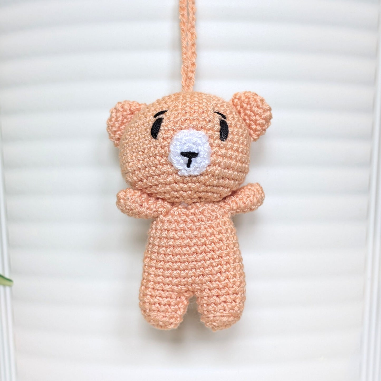 Peach colored crocheted mini teddy bear bag charm with string