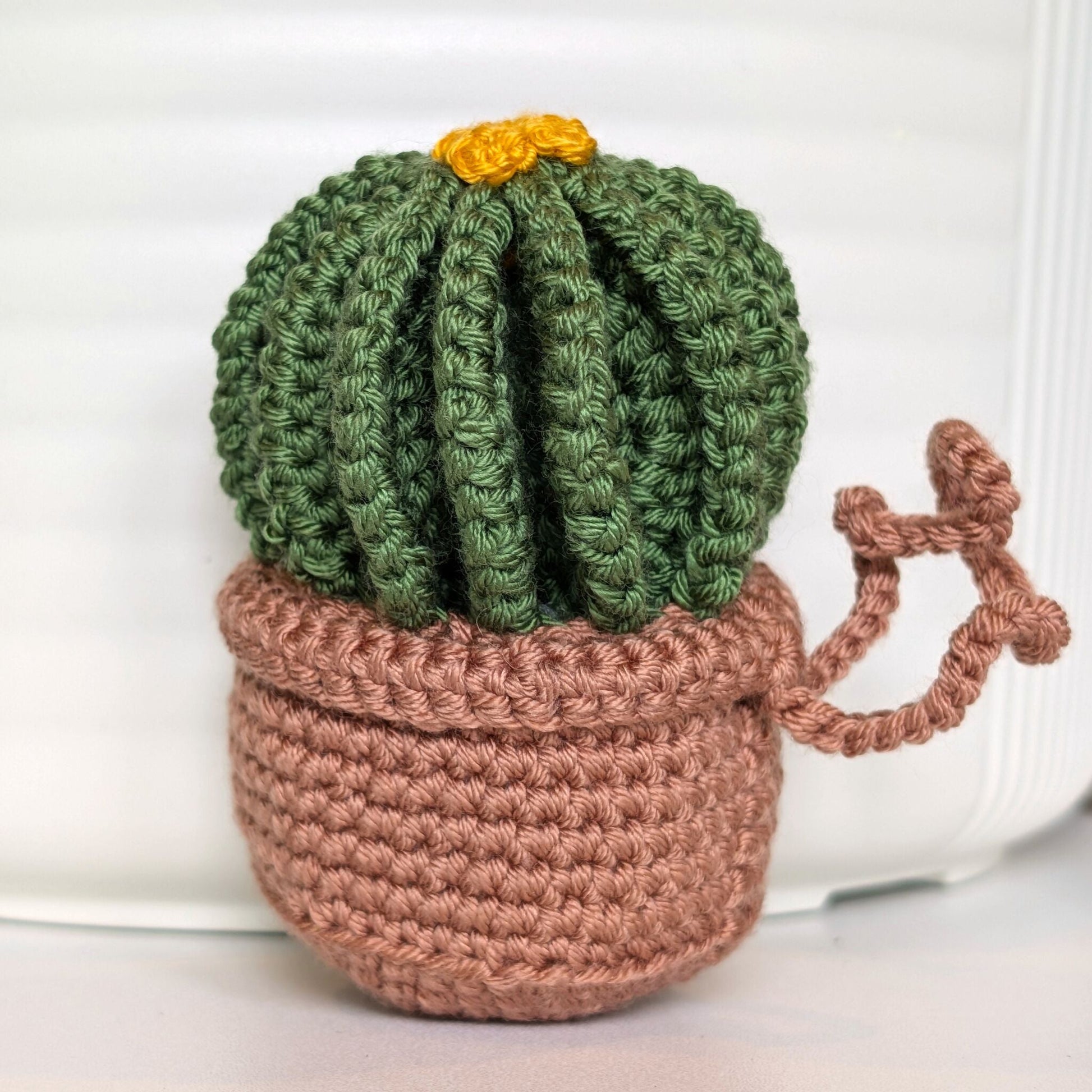 Crocheted golden barrel cactus in a blush brown pot with an amber flower and a string