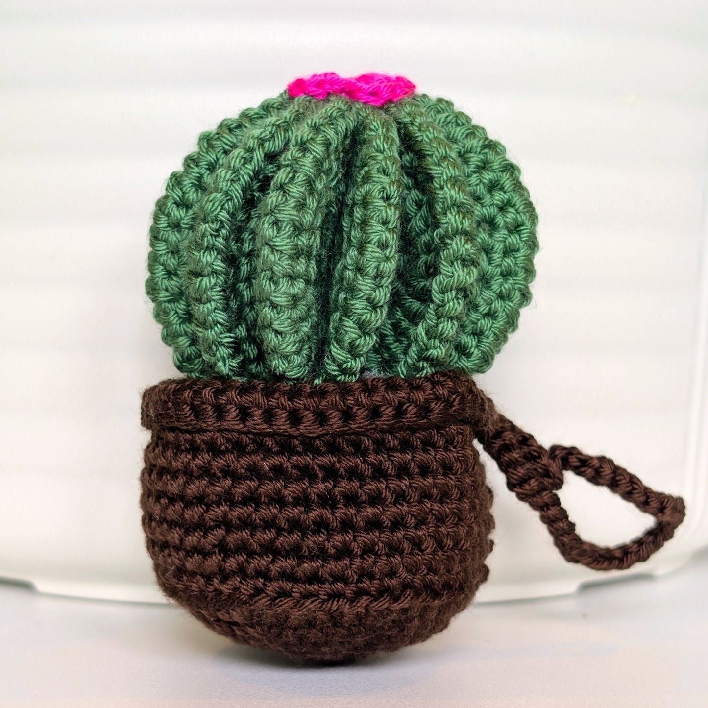 Crocheted golden barrel cactus in a brown pot with a hot pink flower and a string