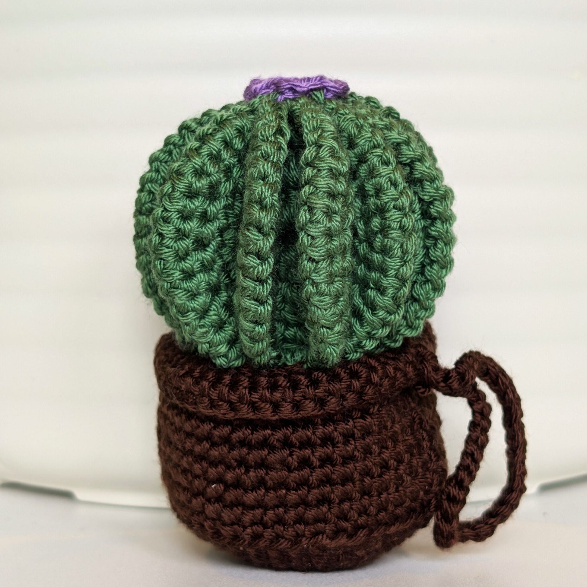 Crocheted golden barrel cactus in a brown pot with a lavender flower and a string