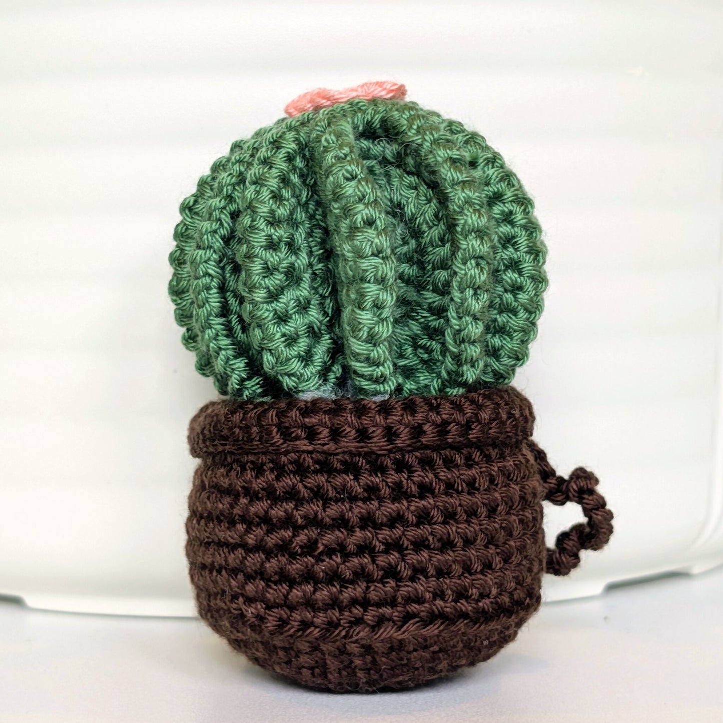 Crocheted golden barrel cactus in a brown pot with a soft melon flower and a string