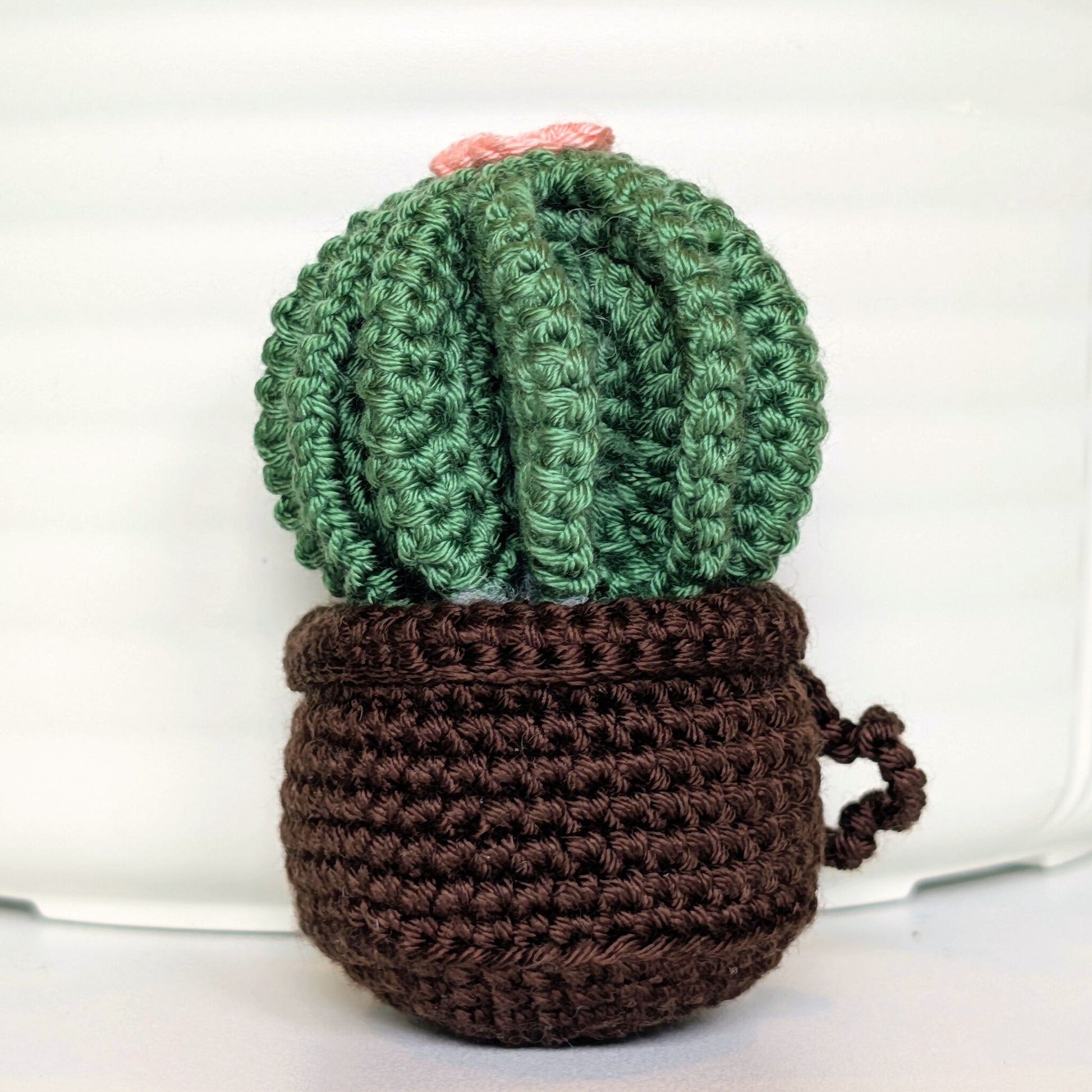 Crocheted golden barrel cactus in a brown pot with a soft melon flower and a string