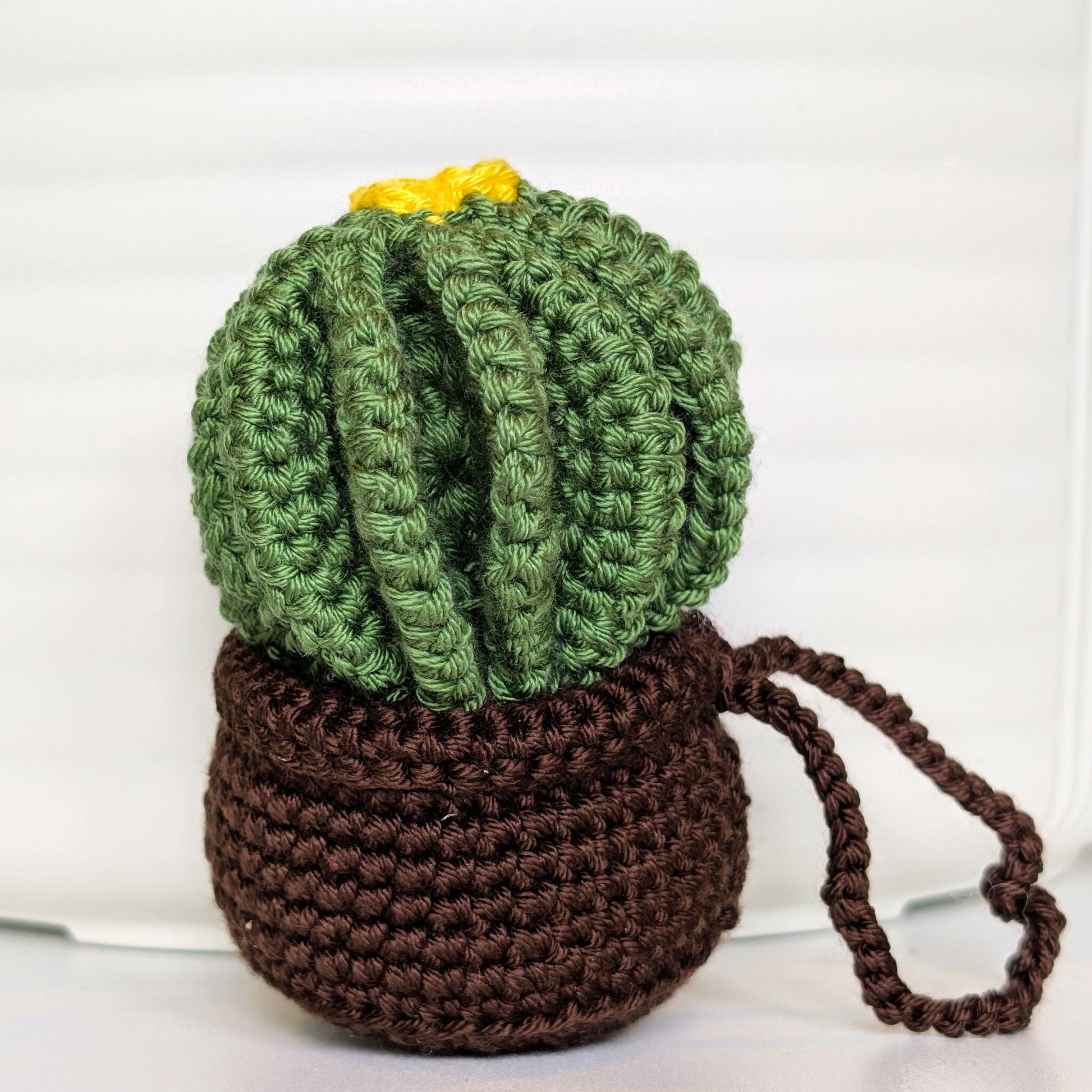 Crocheted golden barrel cactus in a brown pot with a yellow flower and a string