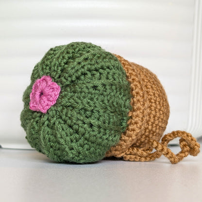 Crocheted moon cactus in a beige pot with a wild orchid color flower and a string