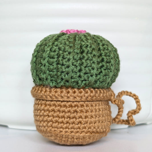 Crocheted moon cactus in a beige pot with a wild orchid color flower and a string