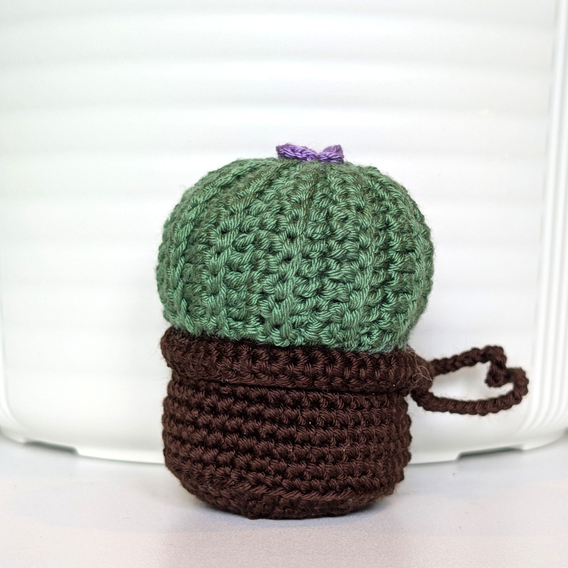 Crocheted moon cactus charm with a lavender flower and attached string, potted in a brown pot
