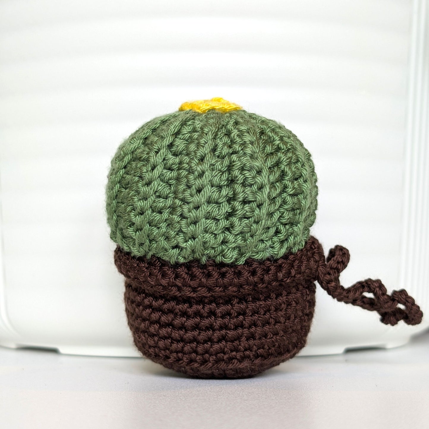 Crocheted moon cactus charm with a yellow flower and attached string, potted in a brown pot