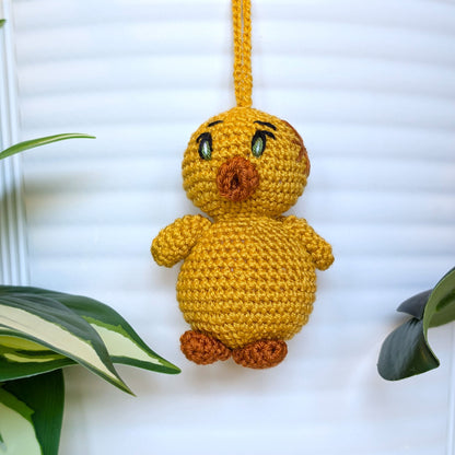 Crocheted golden yellow duck bag charm with string wearing star hair accessory