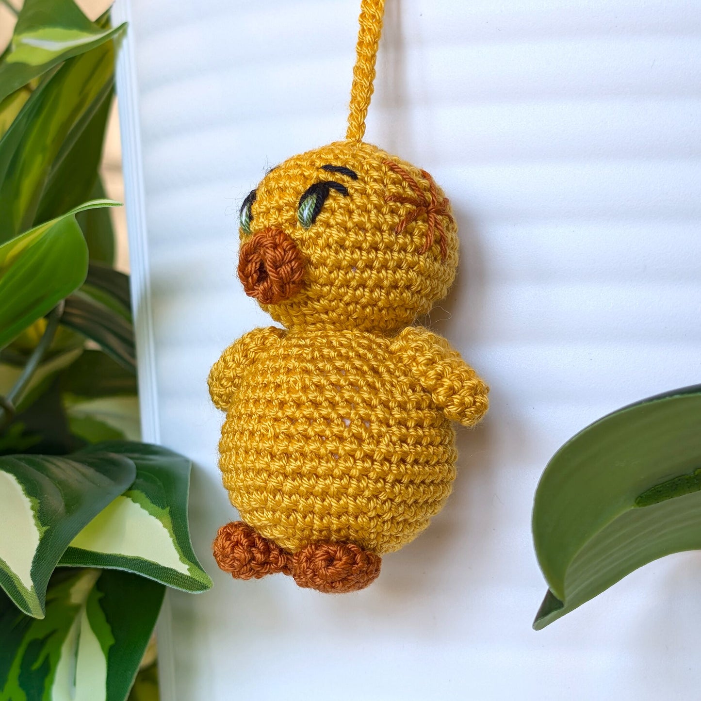 Side view of crocheted golden yellow duck bag charm with string wearing star hair accessory