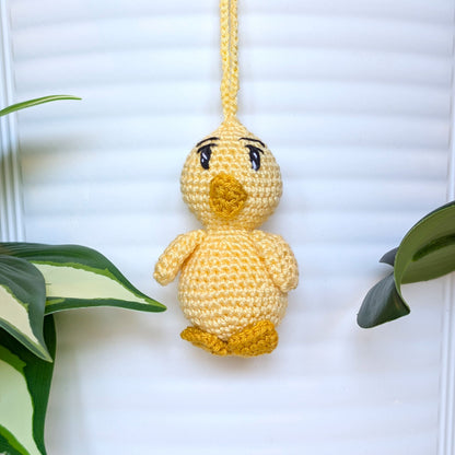 Crocheted light yellow chick with sparkly eyes and a string