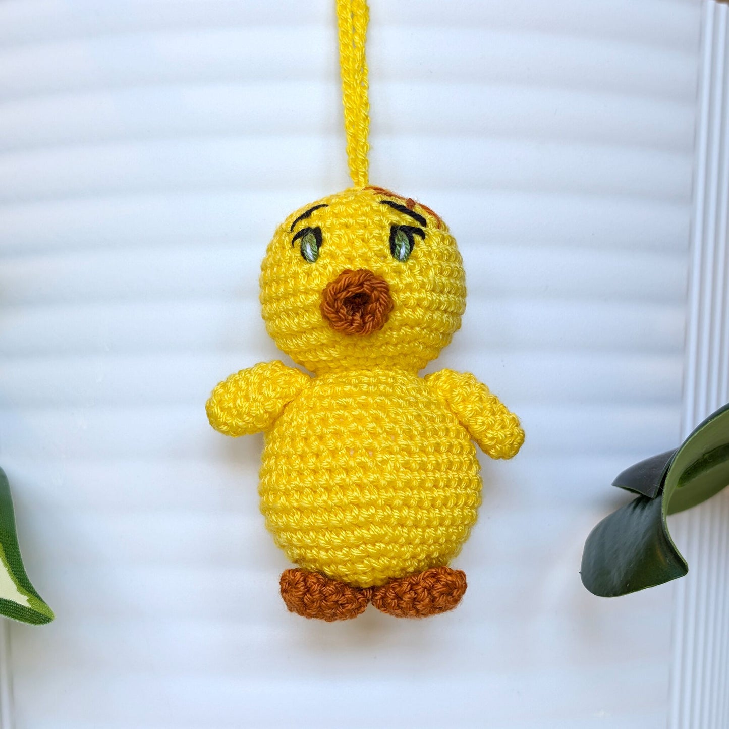 Crocheted yellow chick with green eyes and string wearing a star
