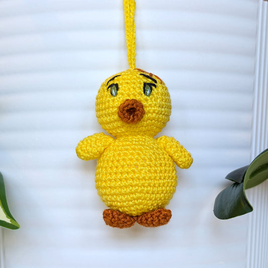Crocheted yellow chick with green eyes and string wearing a star