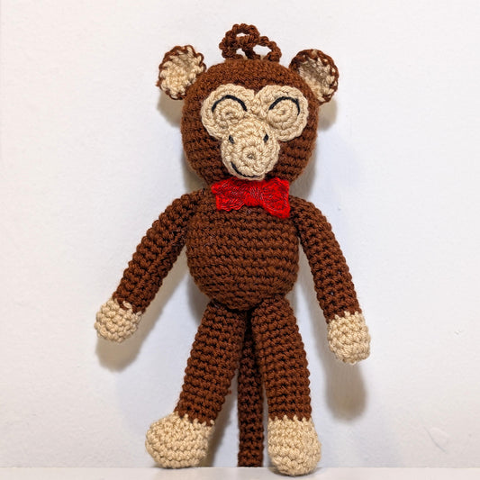 Standing crocheted chimpanzee wearing a red bow tie, attached to a string