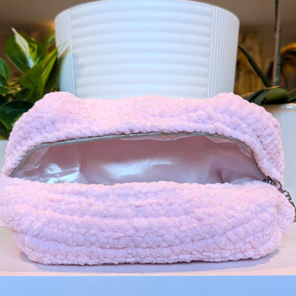 Light pink crocheted bag with a zipper and white satin lining