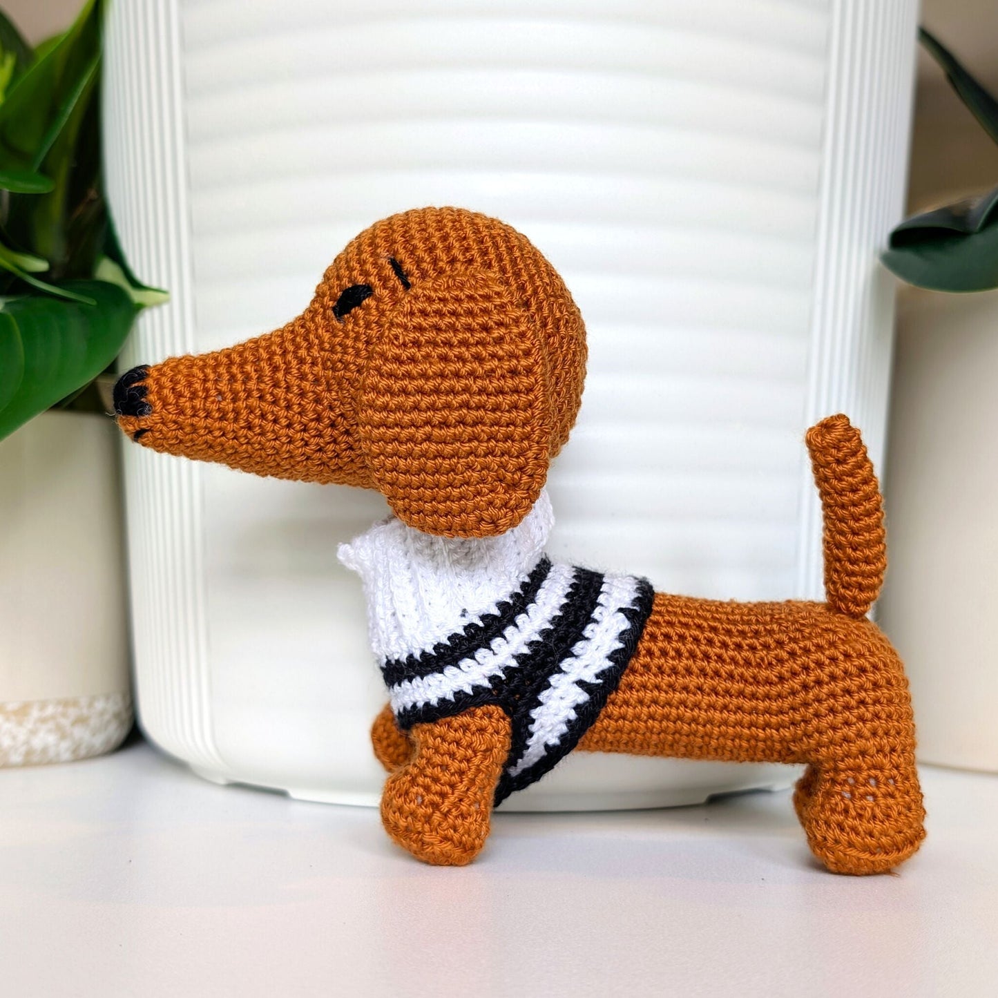 Crocheted dachshund dog toy plush wearing a black and white striped sweater