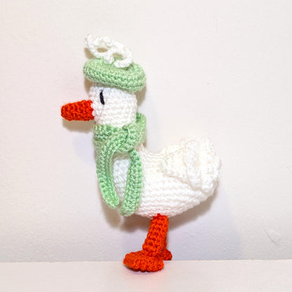 Crocheted duck keychain charm wearing a mint green beret and scarf, attached to a string