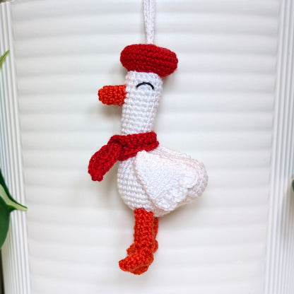 Crocheted duck keychain charm wearing a red beret and scarf, attached to a string
