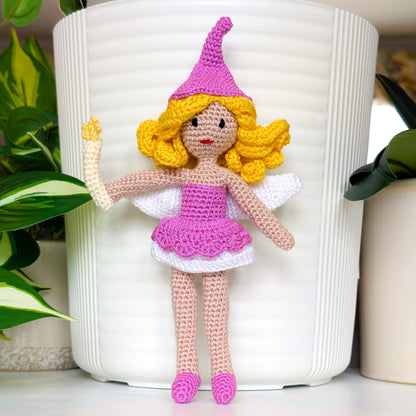 Crocheted fairy doll with pink outfit and yellow hair holding a wand