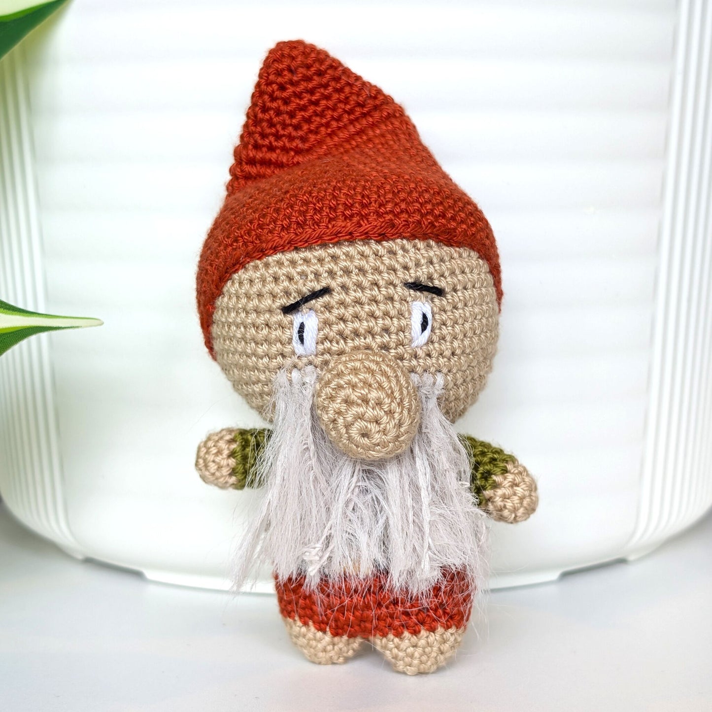 Crocheted plush gnome toy with a terracotta red hat and light gray beard 