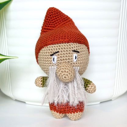 Crocheted plush gnome toy with a terracotta red hat and light gray beard 