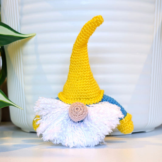 Handmade crochet Scandinavian gnome with a sunflower yellow hat, azure blue shirt, and white beard 