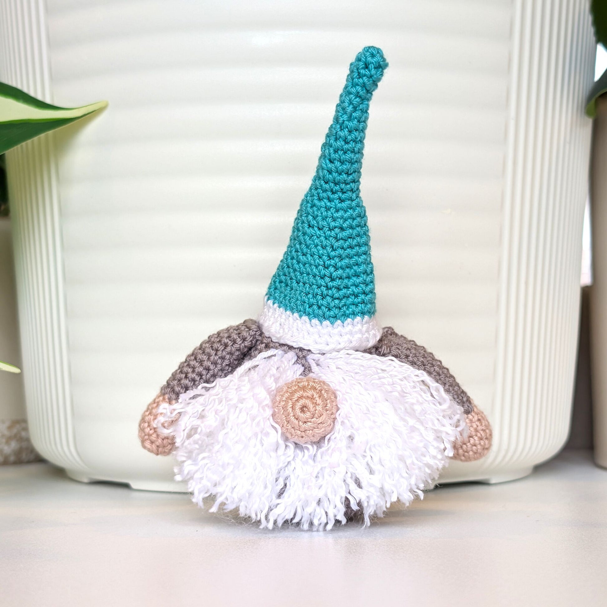 Nordic coastal gnome amigurumi figurine with a light teal hat and on a white surface