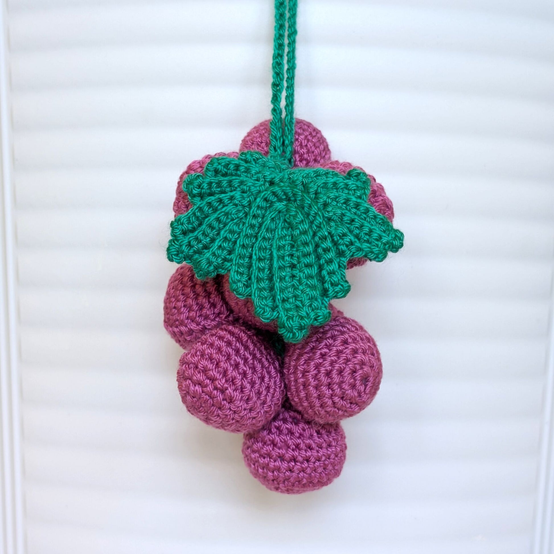 Crocheted purple grapes with a green leaf and string