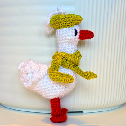 Crocheted duck keychain charm wearing a chartreuse beret and scarf, attached to a string