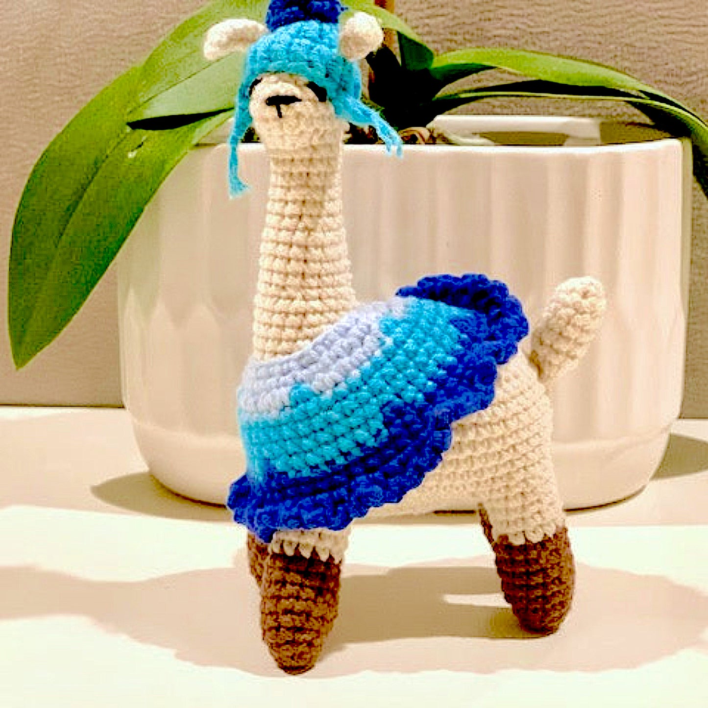 Crocheted llama figurines with blue attire and hat 