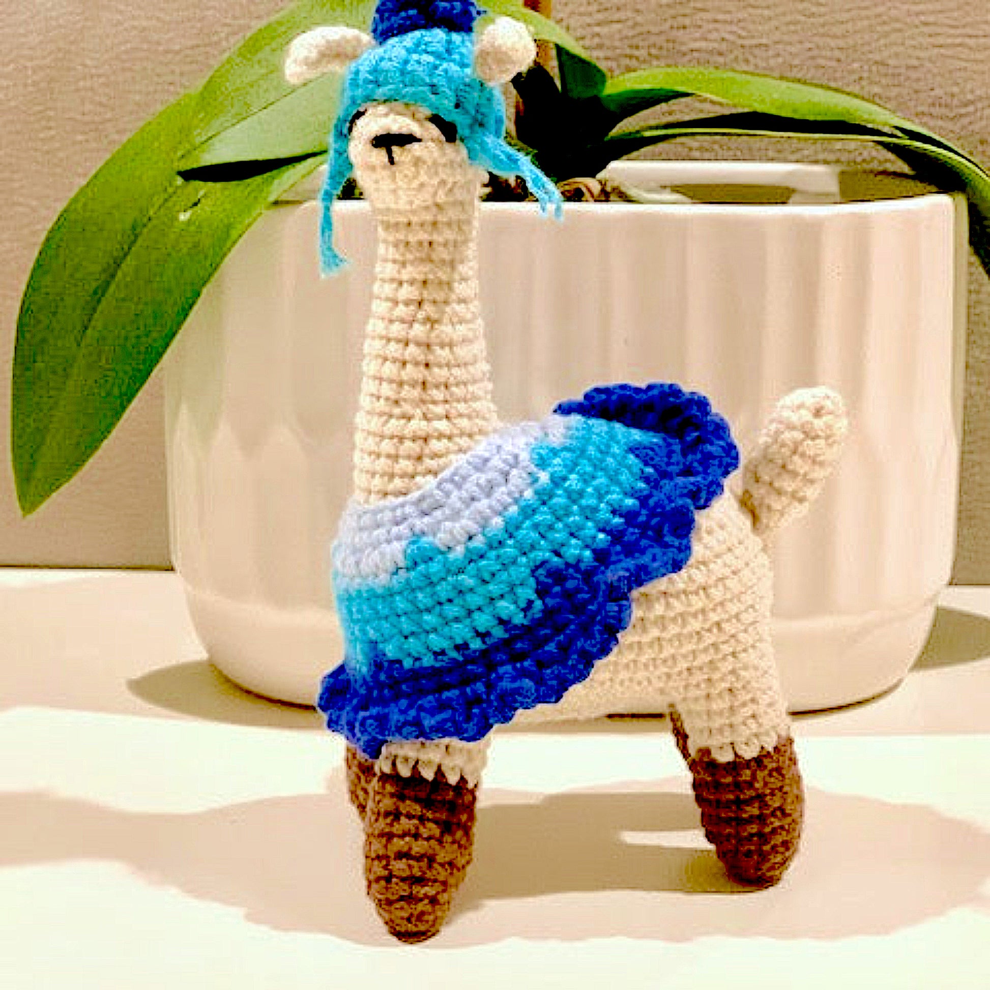 Crocheted llama figurines with blue attire and hat 