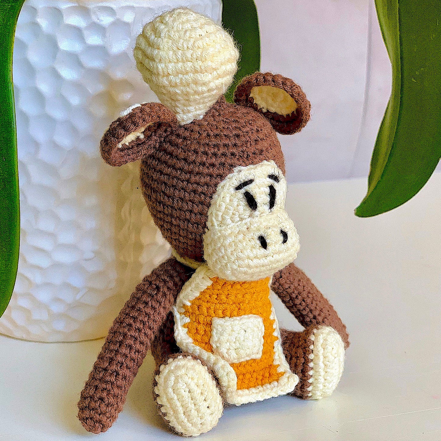 Crocheted plush monkey toy dressed like a chef.