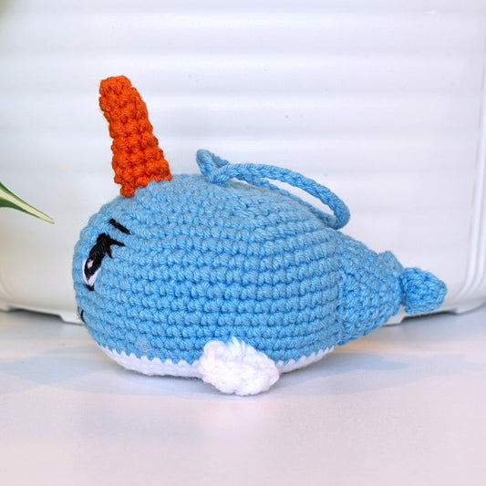 Side view of crocheted light blue plush girl narwhal on string