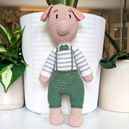 Crocheted standing pig wearing a striped sage green sweater, gray pants and a bow tie