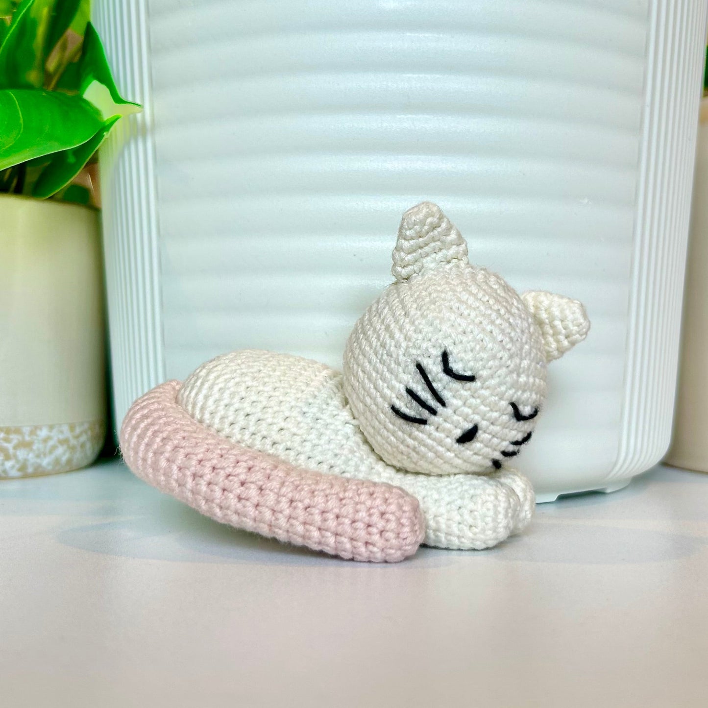 cream crocheted sleeping cat with a seashell pink tail